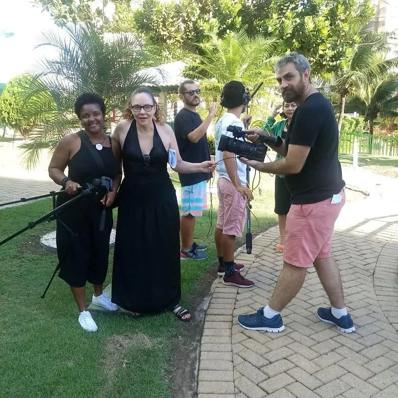 Equipa de filmagem num jardim, com câmara, tripé e microfone.