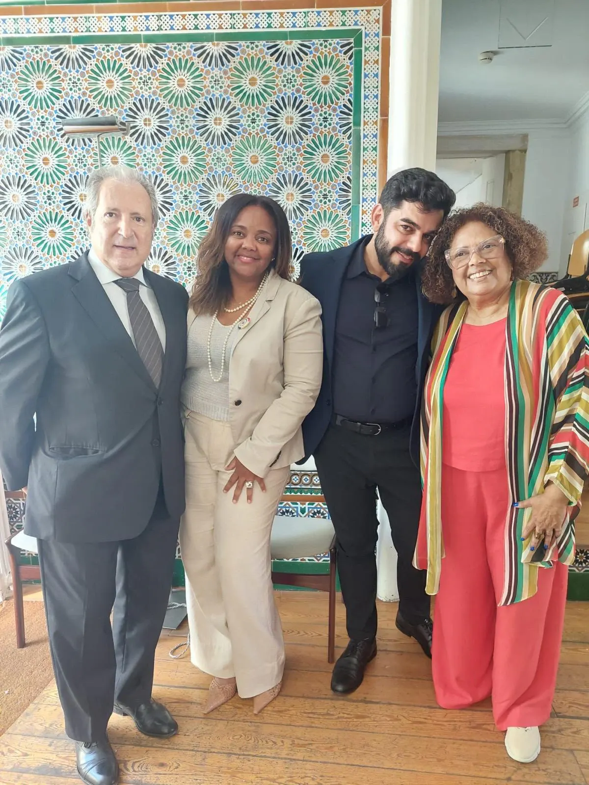 Aline Souza com convidados num evento em Lisboa, diante de um painel de azulejos.